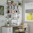 An organized home office space with office organizer shelves above a desk, displaying books, decorative items, and plants, near a window with a view of lush greenery, paired with a contemporary office chair.