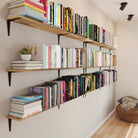 Wall-mounted shelves packed with colorful books. This library-style setup offers smart vertical storage and a bold, lived-in aesthetic ideal for reading nooks or hallways.