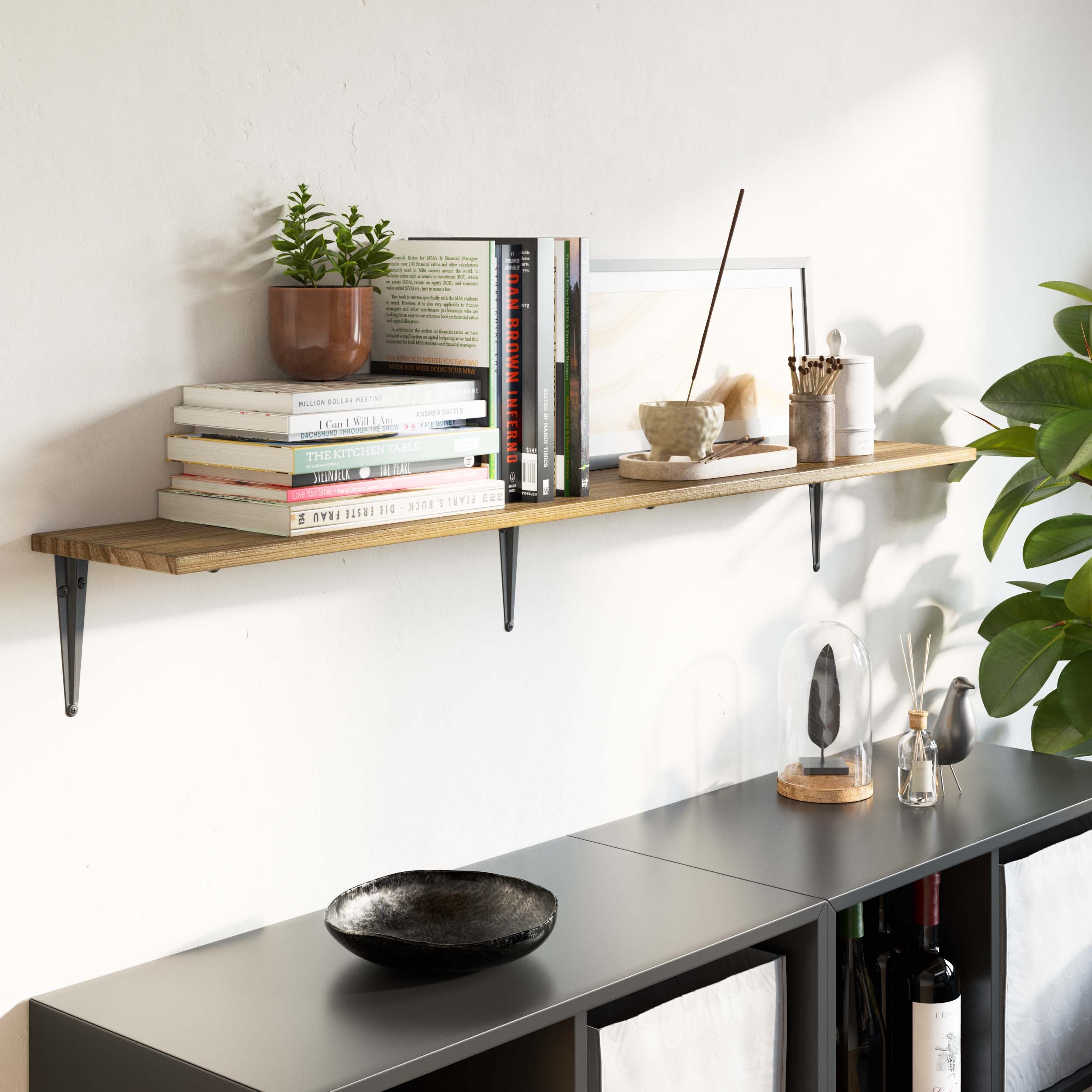 Wall-mounted shelf above a black cabinet, styled with books, incense sticks, and minimalist decor, creating a calm, serene vibe in the living area.