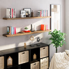 Two rustic wood floating shelves mounted above a black cubed storage unit. The setup holds books, vases, art, and plants, enhancing a cozy, stylish living space with natural texture and a clean, organized feel.