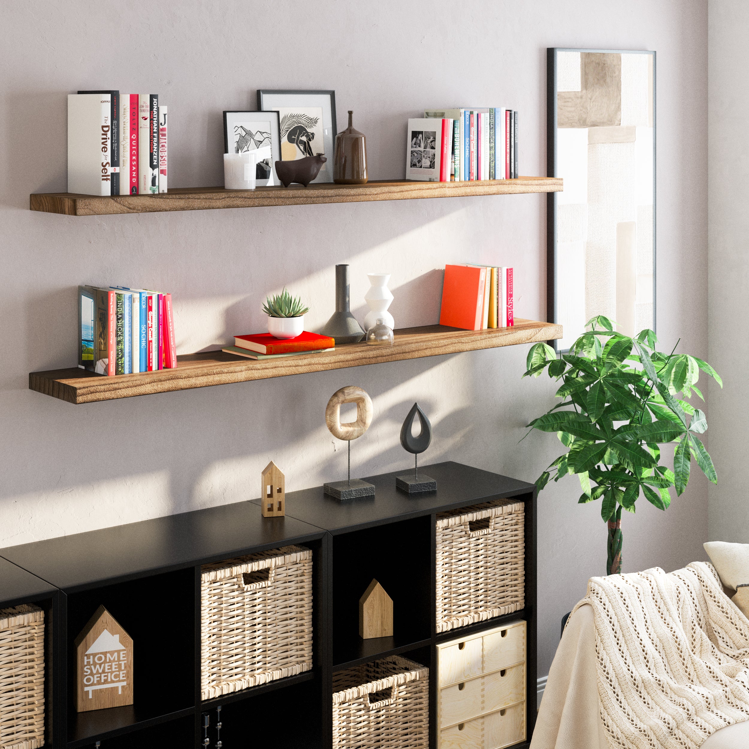 Two rustic wood floating shelves mounted above a black cubed storage unit. The setup holds books, vases, art, and plants, enhancing a cozy, stylish living space with natural texture and a clean, organized feel.