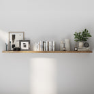 A sleek floating shelf styled with monochrome books, candles, framed prints, and a small plant. A minimalist and balanced design for modern living spaces.