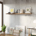 A living room setup with art frames, cactus, and a rustic hidden bracket shelf displaying a camera, candles, art frames and vintage books on a rustic wall decor