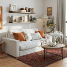 Two 48 inch long wall bookshelves with invisible brackets in a dark walnut finish styled with books and vases over a cozy white couch. Warm tones and framed art create a welcoming living room aesthetic.