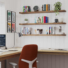 Three rustic office shelves display books, DVDs, plants, and vases in a vibrant and practical living room, blending storage and decoration with ease.