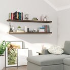 Two wood floating shelves with hidden brackets above a sofa corner, featuring books, decor items, and framed art. A cozy, modern reading nook with a relaxed ambiance.