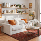 Two 72 inch long floating shelves in a special walnut finish with invisible brackets styled with books and vases over a cozy white couch. Warm tones and framed art create a welcoming living room aesthetic.