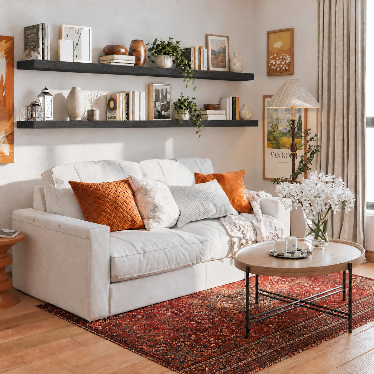 Two 72 inch long floating shelves in a ebony finish with invisible brackets styled with books and vases over a cozy white couch. Warm tones and framed art create a welcoming living room aesthetic.