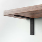 Black metal L-shaped bracket securely supporting a wooden shelf for modern storage solutions.