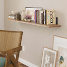 Floating shelf in living room supported by black metal L brackets, displaying books and decor.