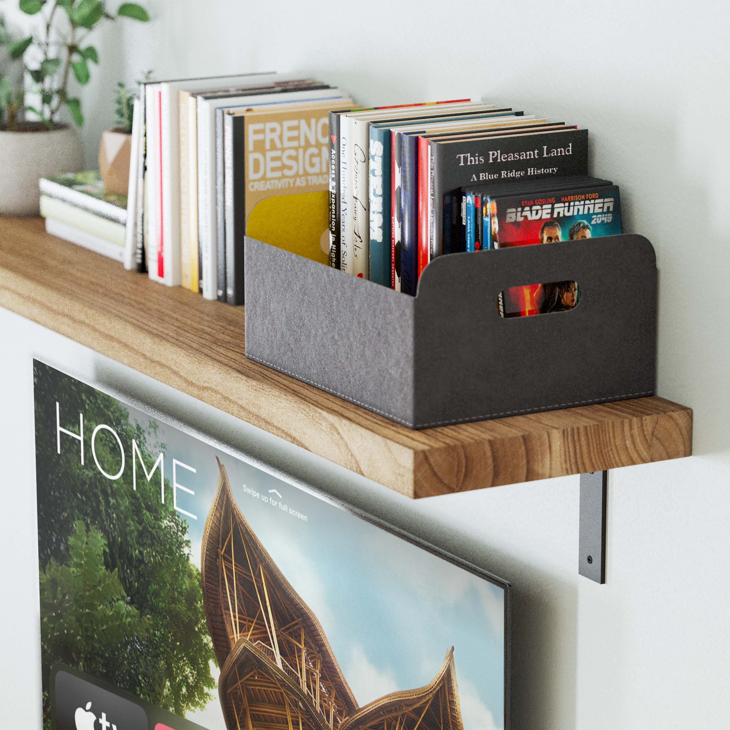 A close-up of a floating book shelf with a variety of books and a felt organizer box, mounted above a TV screen with "HOME" on the display.