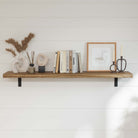 A stylish hanging shelf for wall with artistic decor, including sculptures, pampas grass, a reed diffuser, books, a framed line drawing, and candle holders.
