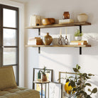 Living room shelves with burnt color styled with books and ceramic decor. A nearby couch and natural lighting make the space inviting and perfect for unwinding with a book.