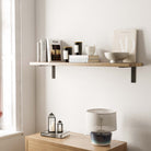 A single long floating shelf styled with minimalist decor items such as candles, books, and bowls, perfect for adding a modern touch to a living space.