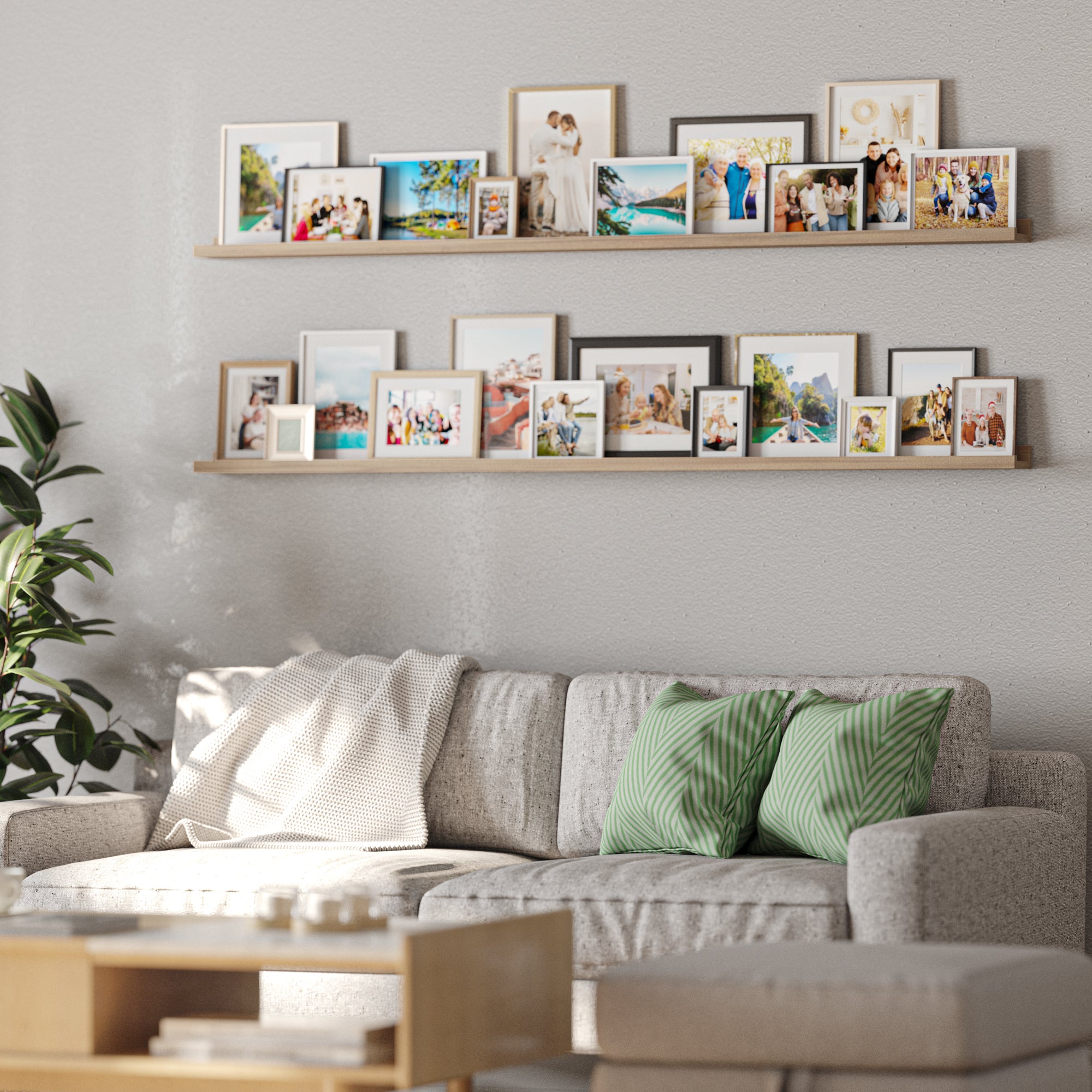 A living room with a cozy couch and green pillows, and above it, two picture shelvesdisplaying a collection of framed photographs.