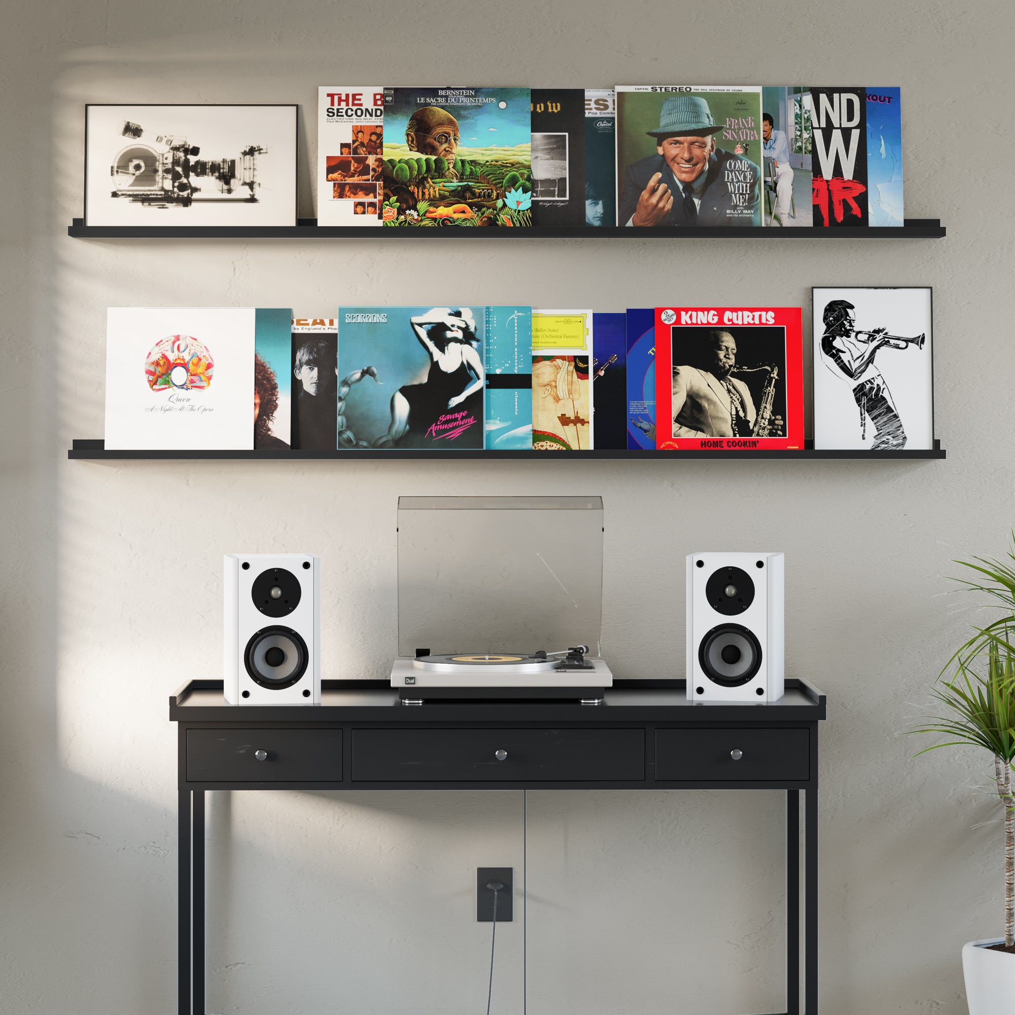 Black wall shelves in a music room with a collection of iconic vinyl records, accompanied by a turntable and speakers.
