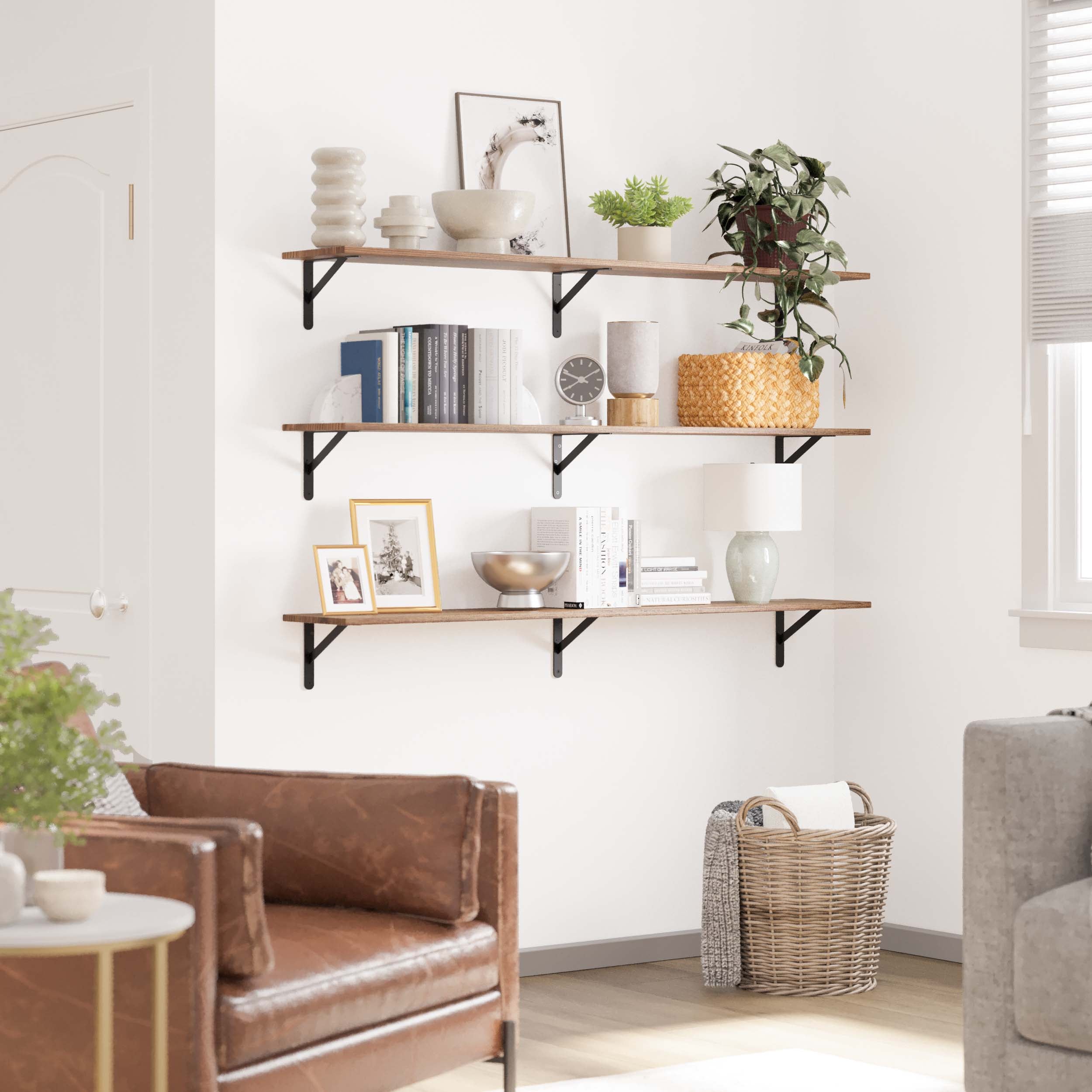 Three-tiered floating bookshelves with black brackets, decorated with books, plants, and decor. It adds a functional yet stylish touch to a bright and modern living space.