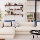 Three wall mounted shelves over a sofa with decor items and books, blending functionality and aesthetics for a cozy living room ambiance.