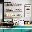 Three  60 inch long coffee shelves in a café setting. Organized with coffee tools, syrups, and products, combining functional storage with a clean, modern look.