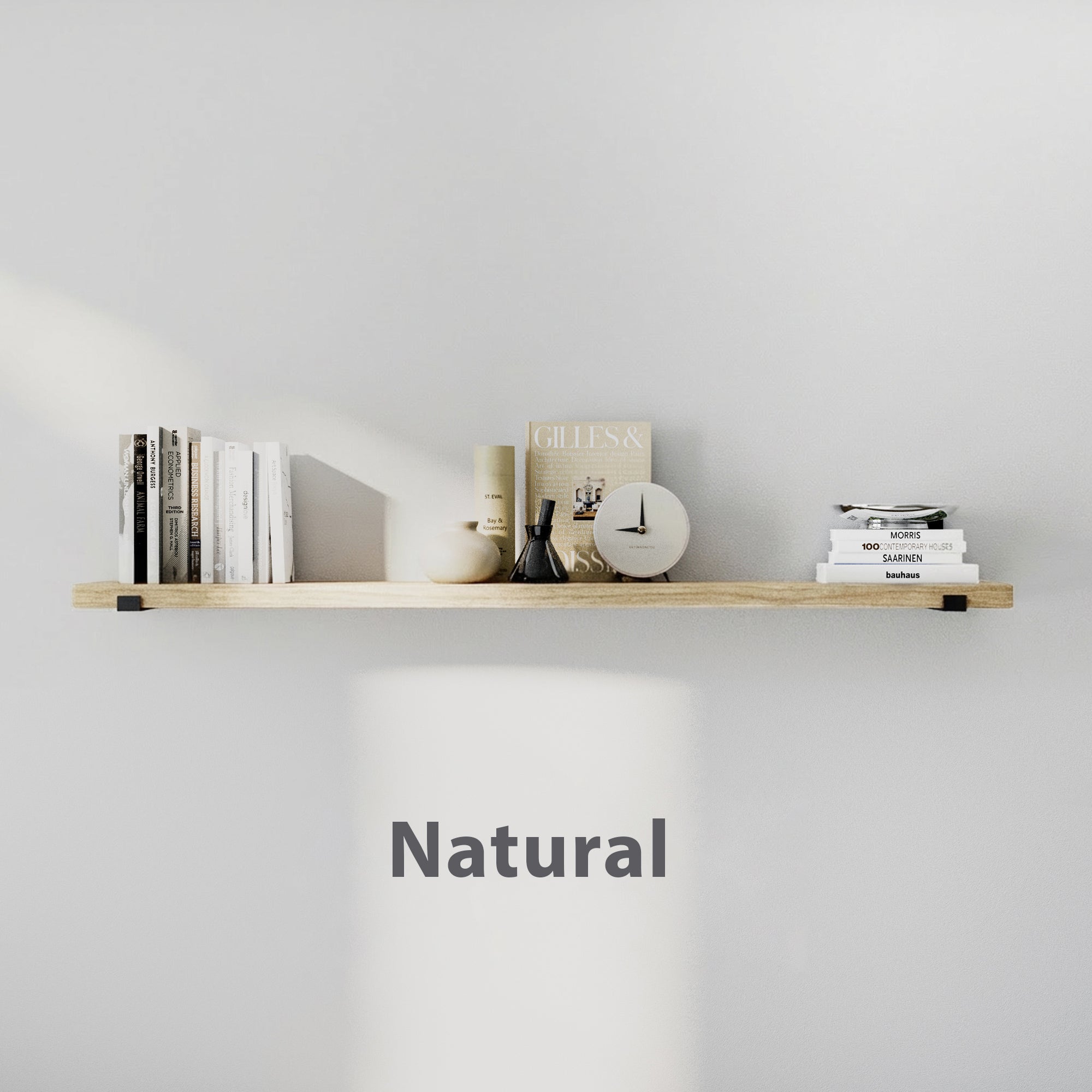 Natural finish floating book  shelf styled with books, candle, vase, and clock. Clean white background highlights the light wood tone and minimalist décor.