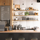 Perfectly organized long storage shelves hold mugs, tea, coffee, and accessories, complementing a warm and inviting cafe environment.