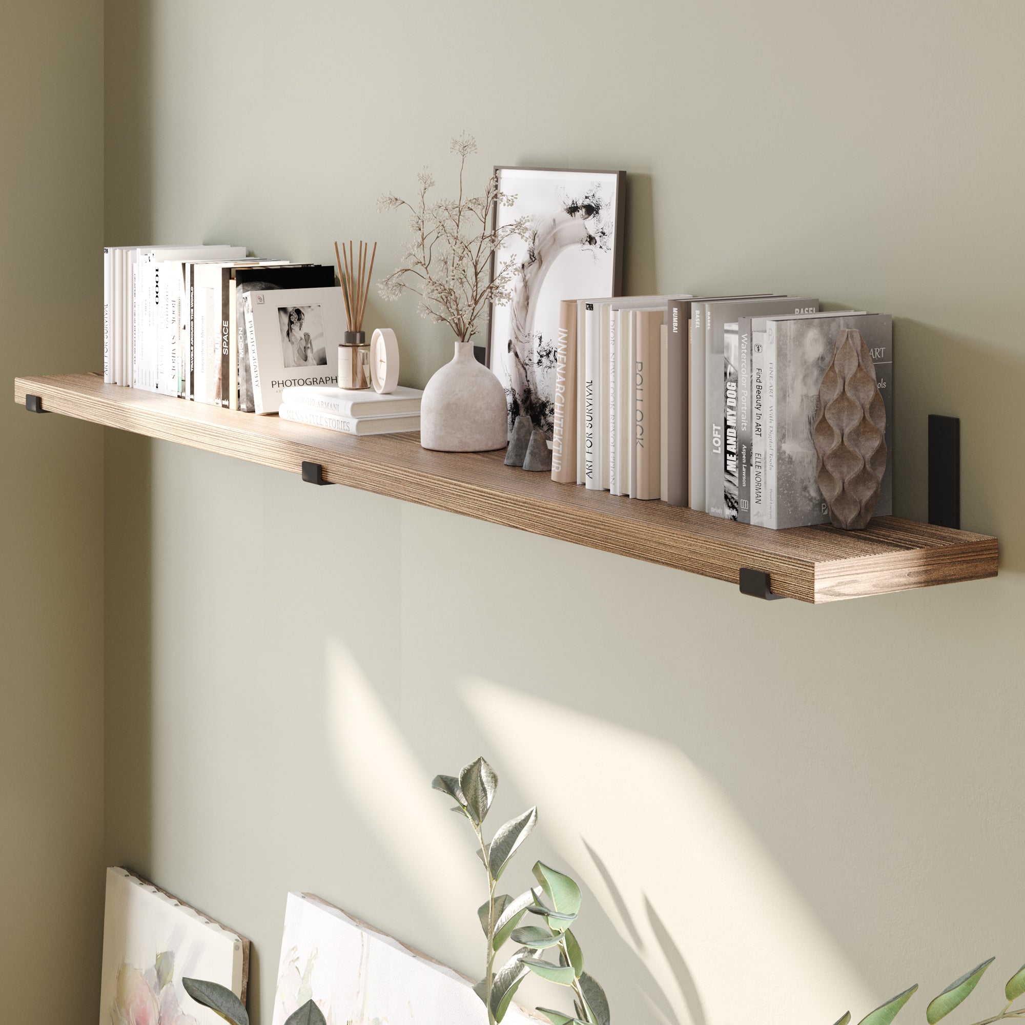 A wall shelf with books, a vase, and framed pictures.