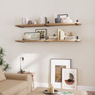 Long rustic shelves adorned with neutral ceramics and framed prints for a cozy living room ambiance.