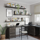 A sleek home office setup featuring three 60 inch long display shelves in rich ebony custom finish holding books, plants, and decor. A matching dark wood desk has a laptop, stationery, and organizers. The room is well-lit with a window and minimalist decor.