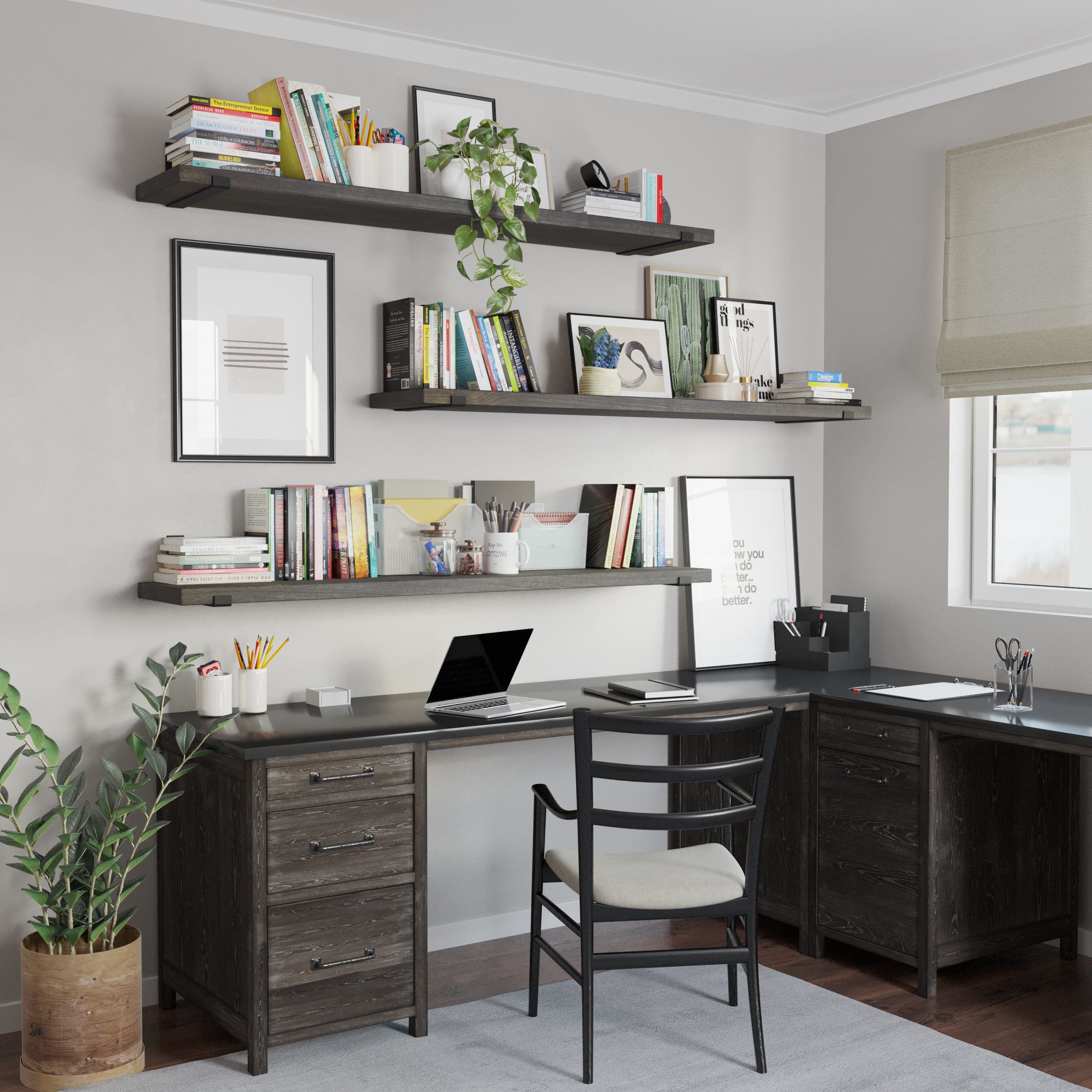 A sleek home office setup featuring three 60 inch long display shelves in rich ebony custom finish holding books, plants, and decor. A matching dark wood desk has a laptop, stationery, and organizers. The room is well-lit with a window and minimalist decor.