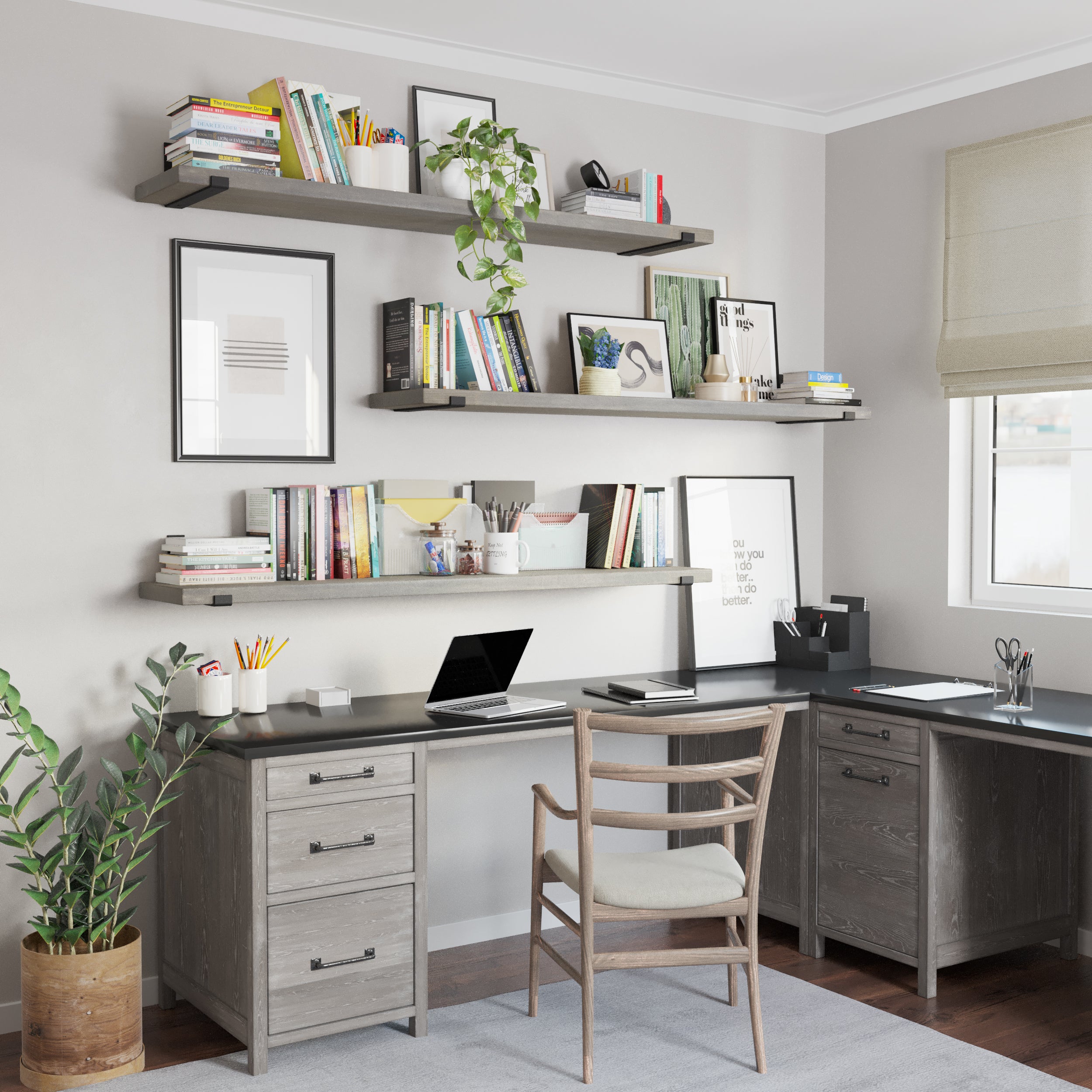 A home office setup with three long wall shelves in rich gray finish displaying books, plants, and decor. Below, a gray desk with a laptop and stationery sits against the wall. A wooden chair and a potted plant complete the cozy workspace.