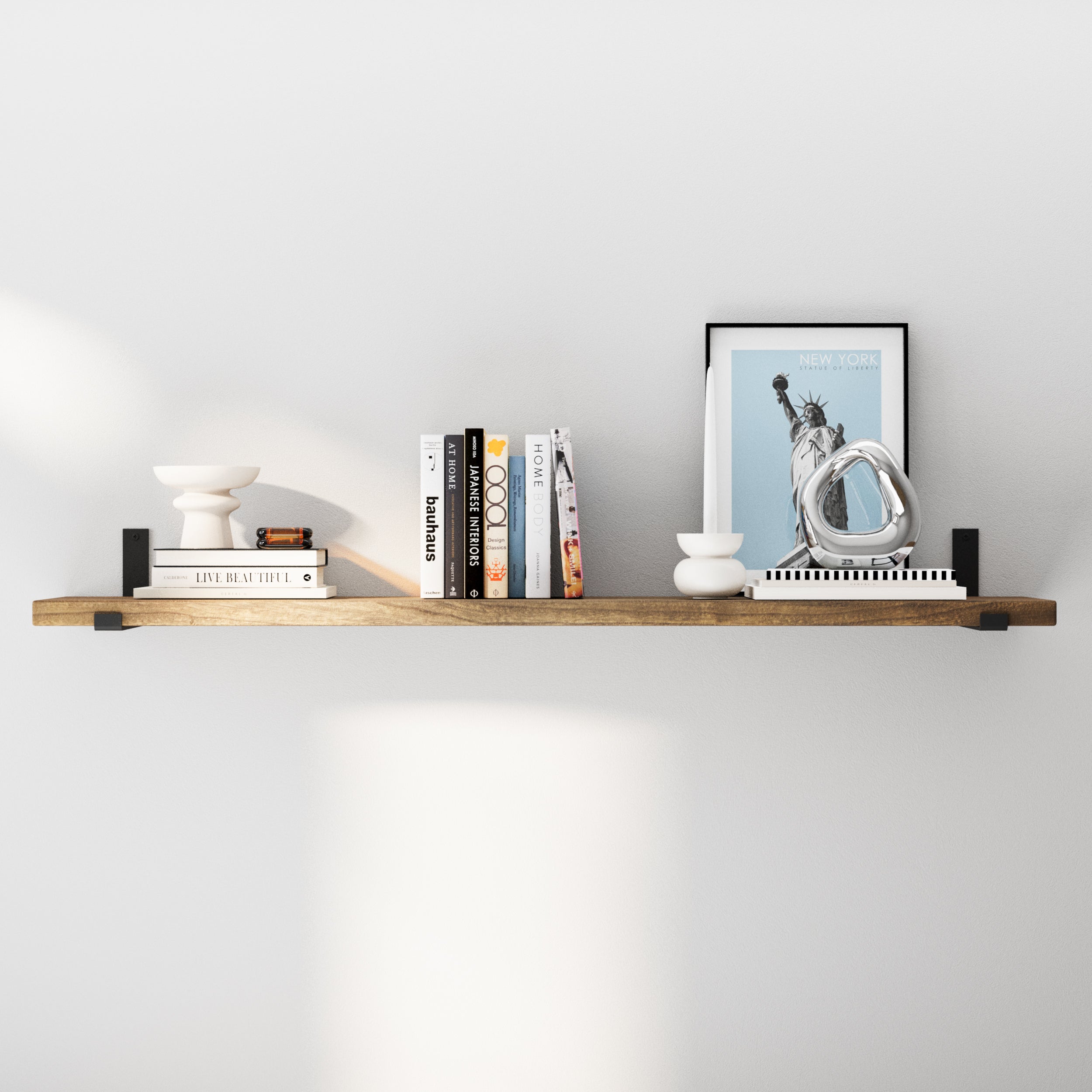 An 60 inch long rustic shelf in a medium  provincial-wood tone finish, styled with diverse decorative elements like books and small sculptures, underlining its adaptability for different room settings.