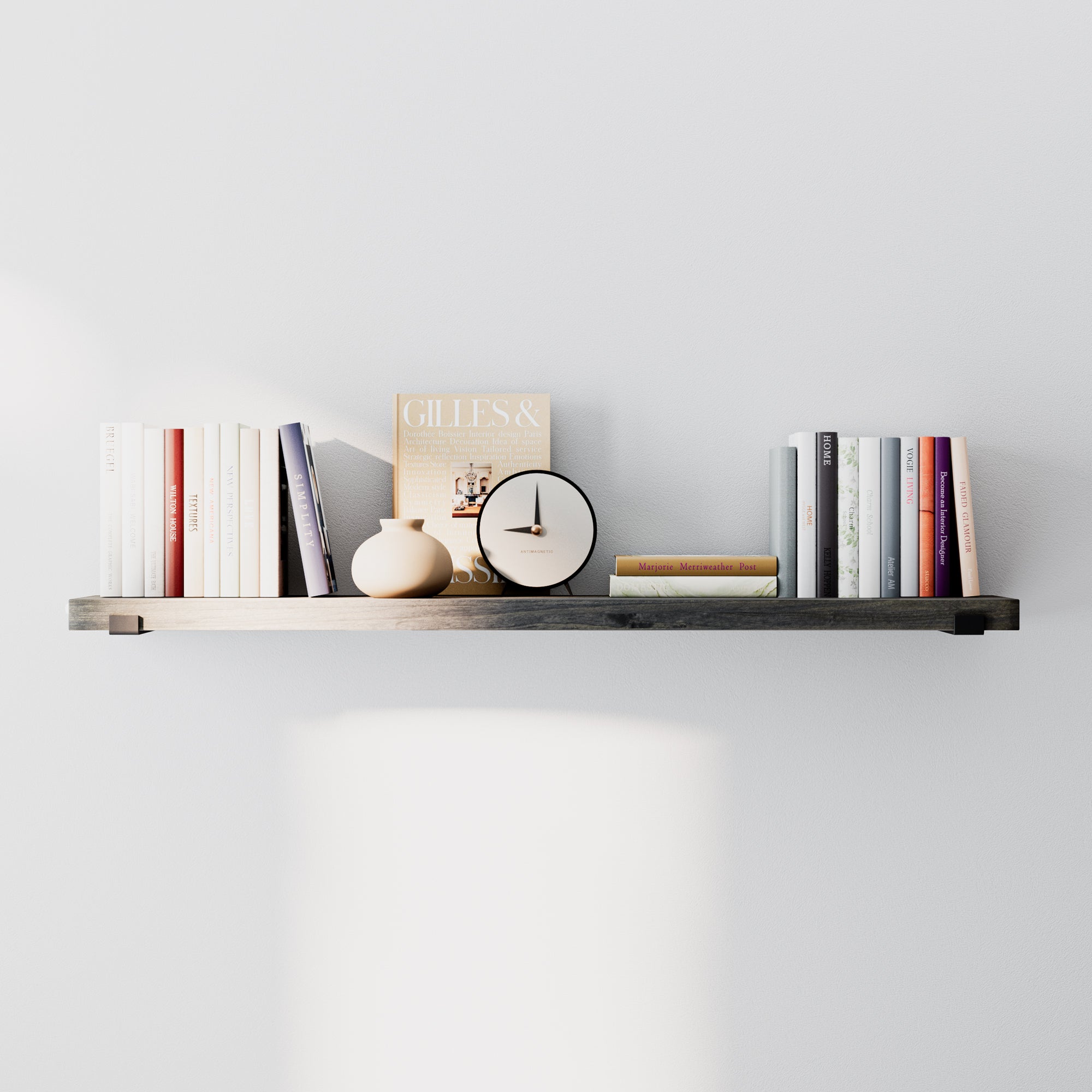 Minimalist floating shelf in sleek ebony finish styled with books, a clock, and decor. Dark wood finish and hidden black brackets create a clean, modern look against a neutral wall.