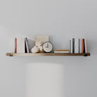 A long decorative shelf in a sleek provincial finish displaying books, a clock, and decorative objects. Balanced, minimalist styling emphasizes length and versatility for modern interiors.