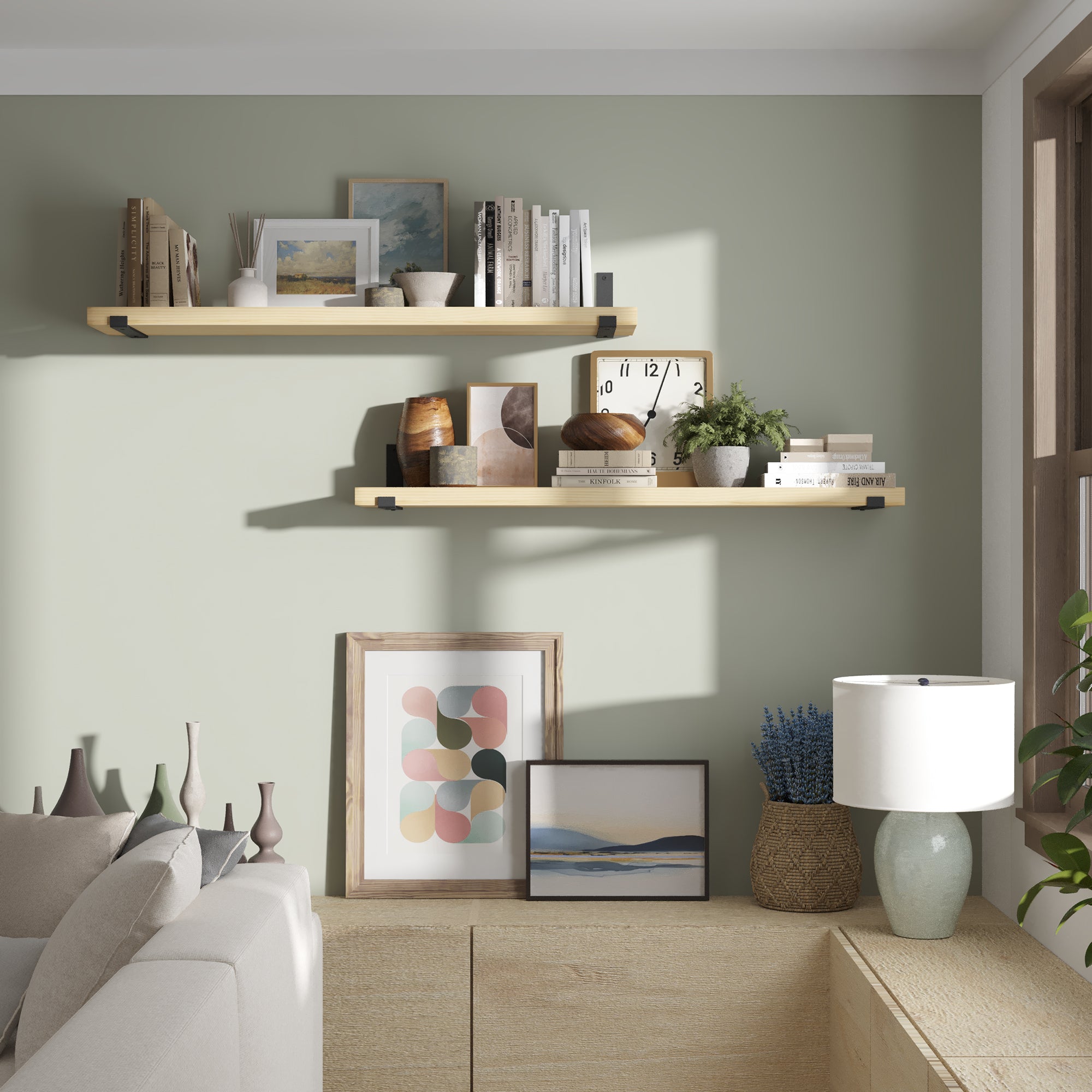 Two living room shelves styled on a sage green wall. Decorated with books, art, and plants, showcasing warm, modern living room storage and décor display.