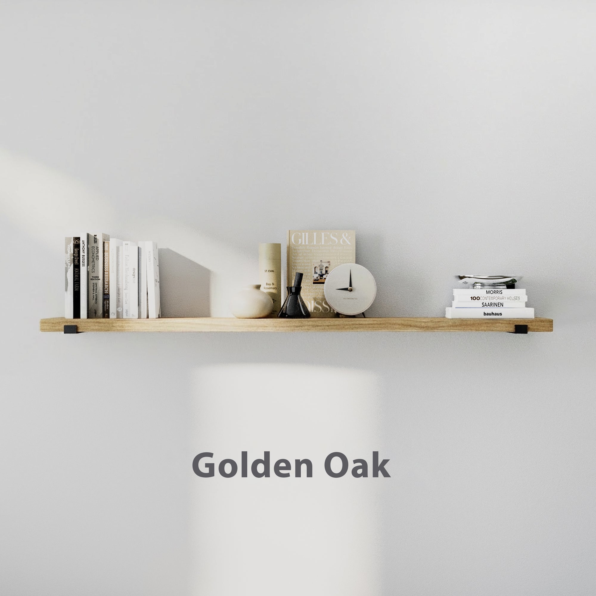 60 inch long golden oak floating shelf styled with books, candle, vase, and clock. Clean white wall highlights warm wood tone and minimalist décor balance.