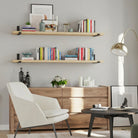 Living room storage decor with a 60 inch long shelf featuring a warm natural finish. Perfect for displaying books, framed photos, plants, and decorative accents while creating elegant floating wall storage with timeless appeal.