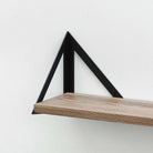 Triangular black metal shelf bracket supporting a wooden shelf for modern home decor.