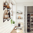 Kitchen with wooden shelves supported by triangular black metal brackets for storage and decor.