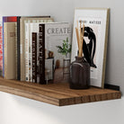 A hanging shelf for wall decor featuring a rich burnt finish and natural wood grain detail. This long shelf offers sturdy wall-mounted storage for books, framed prints, and decorative accents in modern rustic interiors.
