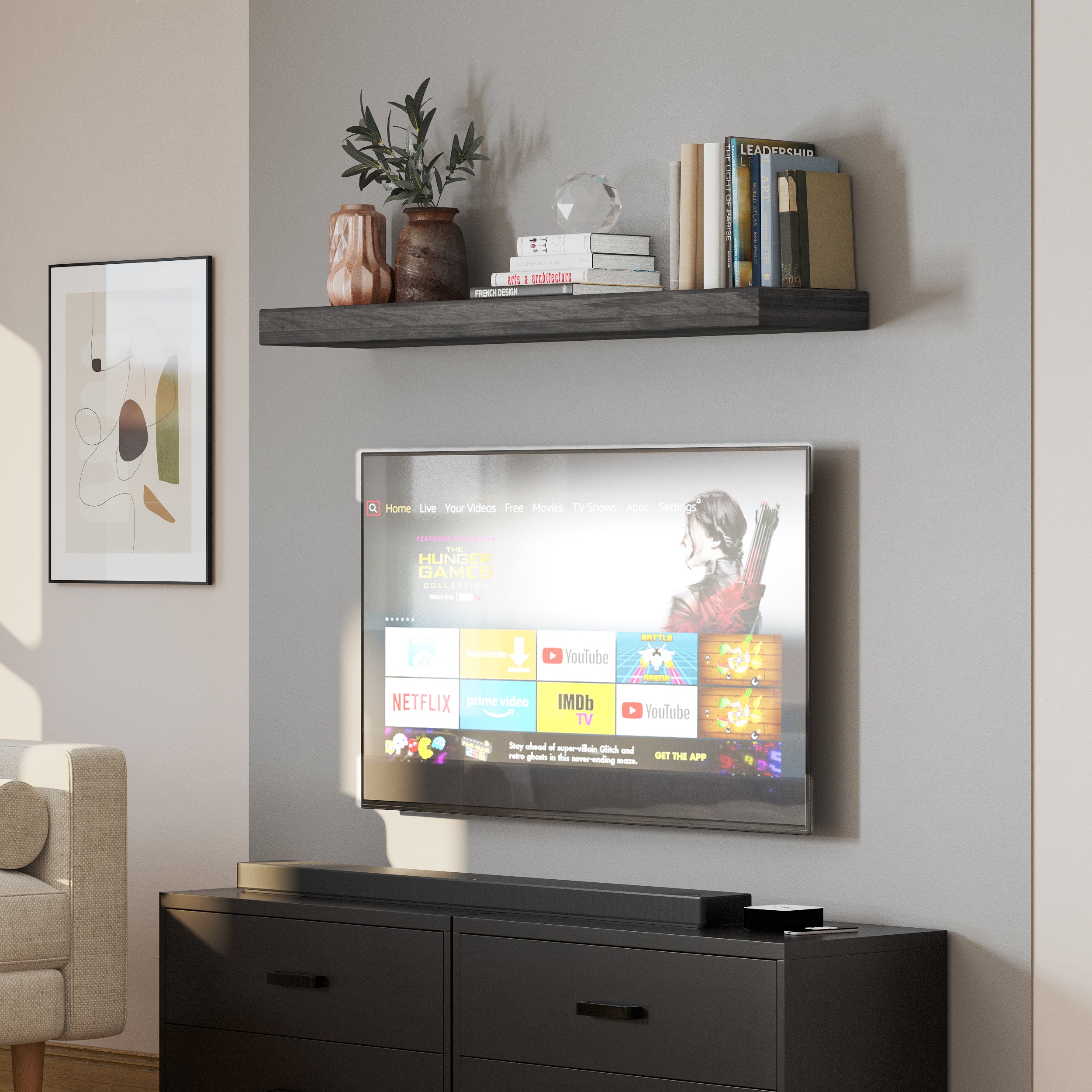 A single ebony floating shelf styled above a mounted TV, holding ceramic vases, a crystal decor piece, and books. A sleek and functional addition to any media wall.