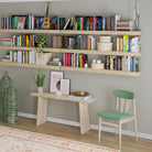 A visually rich setup featuring six natural-finished floating shelves filled with books, greenery, and decorative containers, creating a stylish home library above a rustic bench.