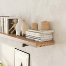 A floating shelf decorated with books, ceramic figures, and small wicker baskets. The shelf is supported by a pipe bracket, adding an industrial touch to the setup.