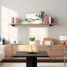 A long display shelf with books, vase, and artworks in a chic living room.