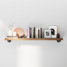 Industrial pipe shelf with decorative items against a white wall