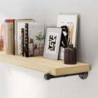 Wall book shelf with books, a vase, and a framed picture against a gray wall.