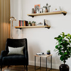 Modern living room with black armchair, entryway shelves, and decorative items.