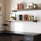 Two  60" black pipe bracket shelves in a rich dark walnut finish in a home office setup, offering stylish wall-mounted storage for books, organizers, and décor. Industrial pipe shelving design blends rustic wood with modern workspace organization.