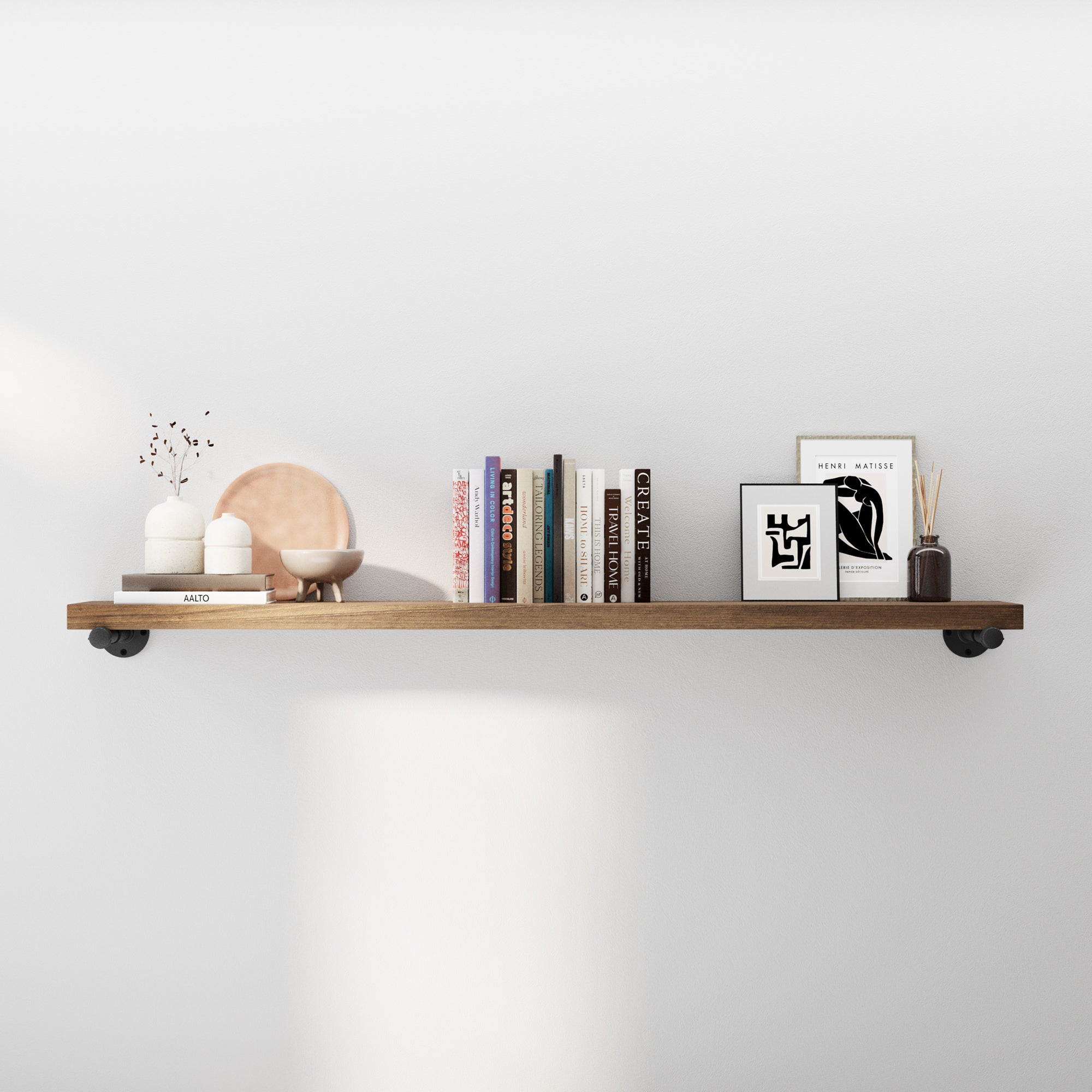 60 inch long floating pipe shelf styled with books and modern décor, featuring rustic wood and industrial pipe brackets. Ideal as a wall mounted bookshelf, living room shelf, entryway storage, or farmhouse wall décor accent.