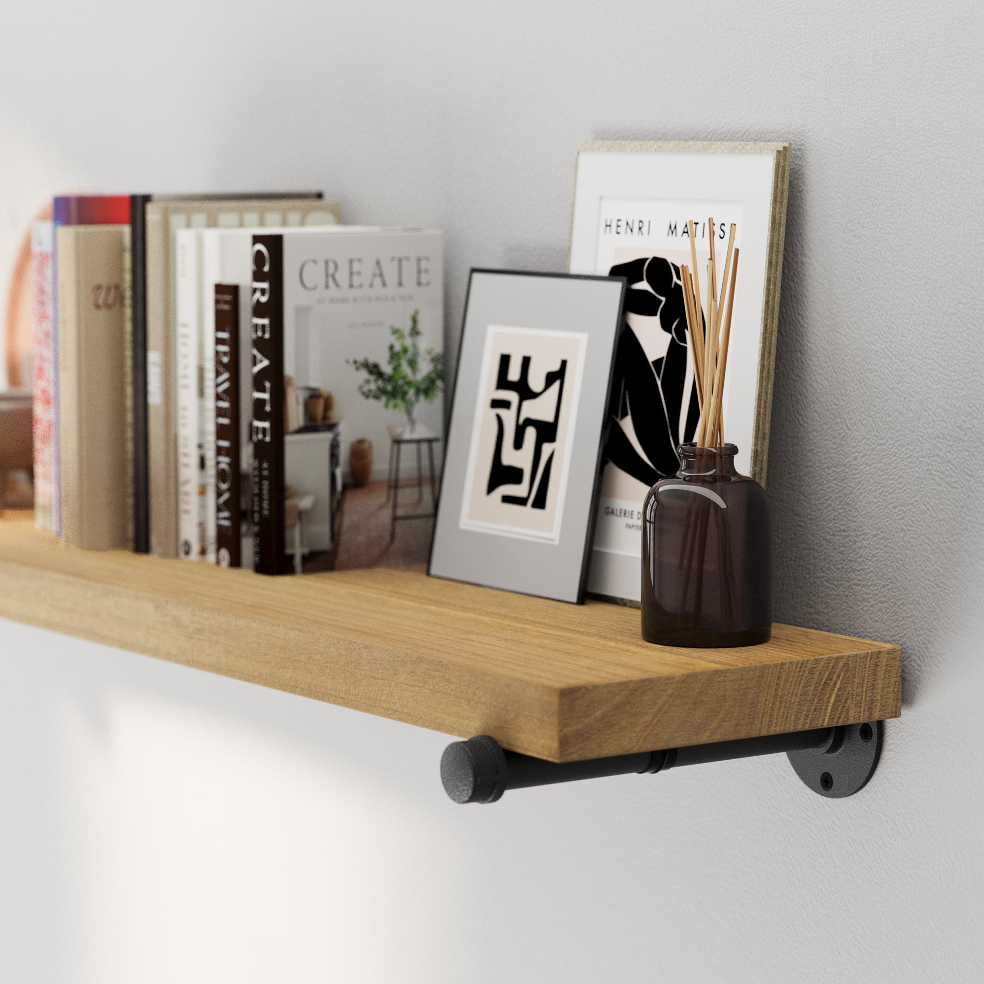 Golden oak floating shelf featuring authentic wood grain and black industrial pipe brackets. A rustic wood wall shelf ideal for displaying framed art, candles, books, or decorative accents in modern interiors.