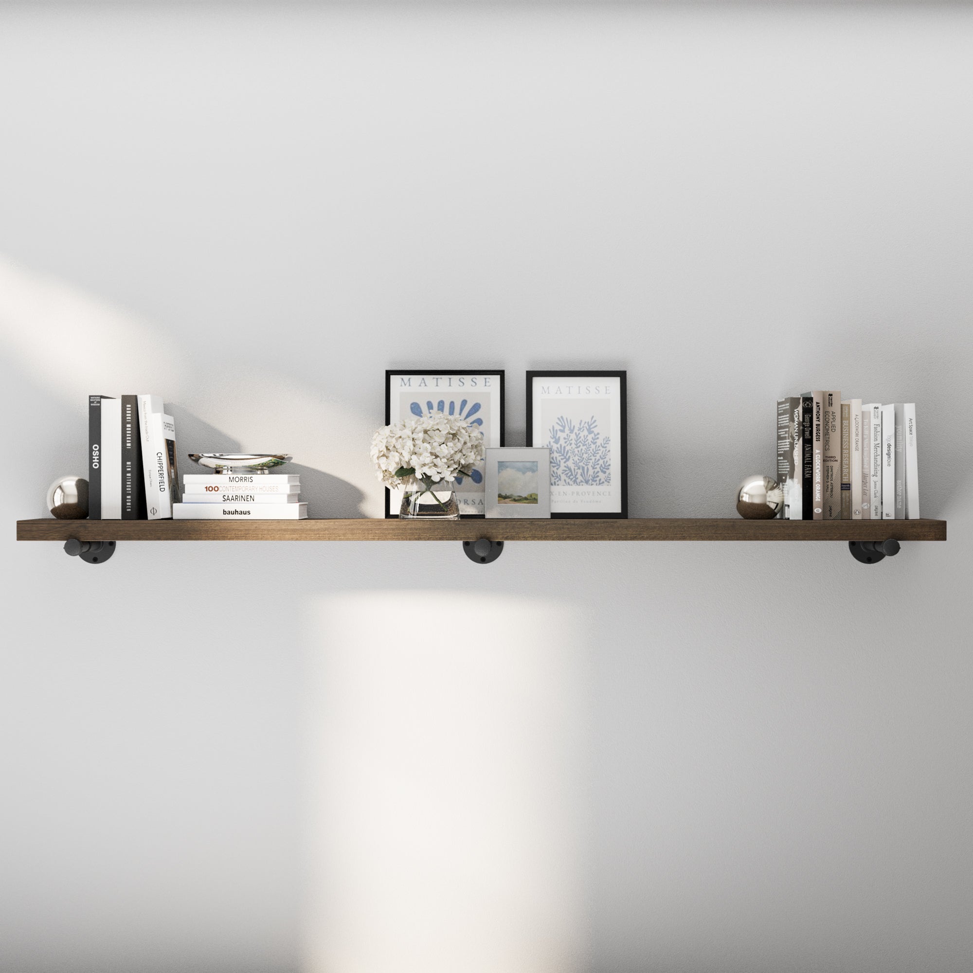 72 inch industrial pipe shelf in a rich dark walnut finish, styled with books and wall décor for a refined rustic-modern look. This extra long floating bookshelf adds elegant storage to living rooms, offices, bedrooms, or kitchens.
